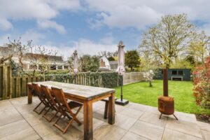 a paved patio with stylish outdoor furniture overlooking a backyard